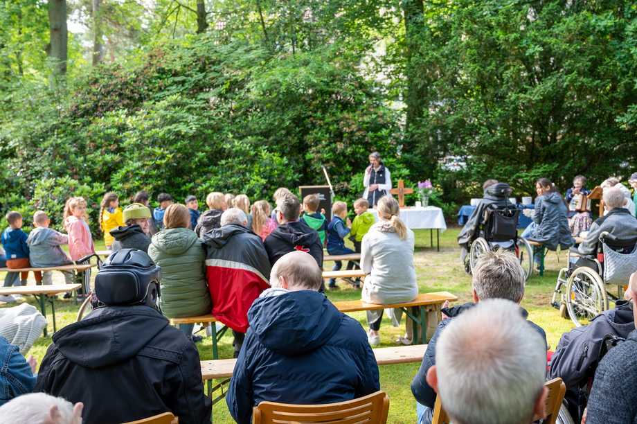 Viele verschiedene Besucher:innen sind beim Waldgottesdienst zu sehen.